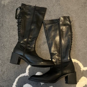 Svarta skinnstövlar - Snygga svarta stövlar i skinn med dragkedja på sidan. Har även snöring där bak så man kan justera den mer. Äkta läder och så fina och classy! Passar mig inte i vaderna därför jag säljer. Mycket lite använda ❤️