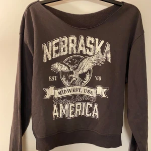 Svart sweatshirt Nebraska print - Cool svart sweatshirt med stort Nebraska-tryck. Tröjan har bred halsringning och långa ärmar💕