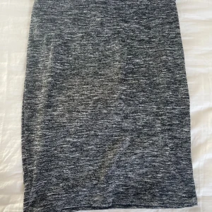 Melerad grå pennkjol från NLY Trend - Säljer en snygg pennkjol från NLY Trend i melerad grå färg. Kjolen är figurnära och har en elastisk midja för skön passform. Materialet är mjukt och stretchigt.