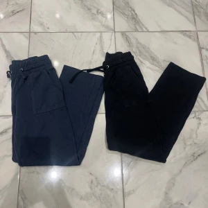 2-pack mjukisbyxor navy & svart 157 S - Två par mjukisbyxor från 157 i storlek S. Ena paret är navyblå och det andra svart, båda med resår och snörning i midjan samt stora fickor framtill. Perfekta för chill dagar eller när du vill vara bekväm. Tillverkade i mjukt bomullsmaterial.