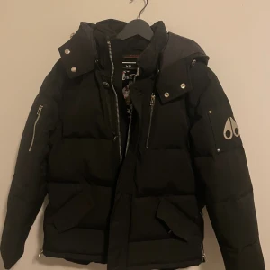 Svart pufferjacka Moose Knuckles - Säljer en svart pufferjacka Moose Knuckles med huva, den är nysikt bara använt den 3-5 gånger 