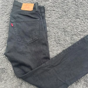Levi's 501® Original Fit Jeans - Svarta Levi's 501® Original - straight fit. Jeansen har fem fickor, knäppning med silverfärgade knappar och Levi’s läderpatchen bak. Materialet är denim i bomull.  Jeansen är i en snygg en snygg helsvart tvätt. Mångsidig jeans som lyfter varje stil. W31 L32. Pris ej hugget i sten! Tveka inte på att hör av dig vid minsta fundering! 😁 