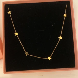 Guldhalsband med stjärnor från Edblad - Superfint halsband i guld från Edblad med små stjärnformade hängen längs en tunn kedja. Perfekt för dig som gillar stilrena smycken med en twist. Justerbar längd med diskret Edblad-logga vid låset. Använd typ 2 gånger 