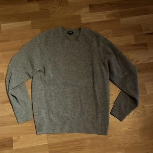 Grå stickad tröja från Uniqlo - En stilren grå stickad tröja från Uniqlo i storlek M. Tröjan har rund halsringning, ribbade muddar och är långärmad. Lite mindre i storlek.