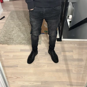 Svarta jeans med slitningar - Riktigt feta jeans med ljus fade och slitningar på benen. Jeansen har en slim passform. Storlek: 31/32. Non branded. Passar riktigt bra på mig som är 180cm och väger 68kg 