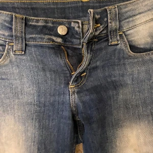 Blå bootcut jeans från Cheap Monday - Snygga blå lågmidjade jeans från Cheap Monday med bootcut-modell och ljusa slitningar längs benen. heansen sälj då de inte används längre. jag har vanligtvis strl S och de passar perfekt. Väldigt små slitningar där nere som man kan se på bilden. Priset kan självklart diskuteras vid snabbt köp!🫶🏽