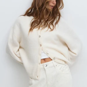 Knitted cardigan  - Supermysig vit/offwhite kofta från ginatricot i storlek XS. Helt slut såld på hemsidan. Stickad kofta med knappar fram. Cardigan är vit och har lös passform. Den har lång ärm, rund halsringning och ribbstickad nederkant