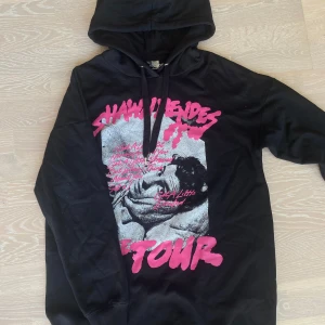 Svart hoodie med coolt tryck⚡️ - Säljer denna hoodie med tryck på Shawmendes  framtill och hans låtar på baksidan. Tröjan har huva med snörning och långa ärmar. Mjuk bomullskänsla och relaxed fit. Hör av dig vid intresse! 