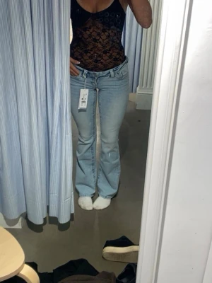 Slutsålda Bootcut ljusblå jeans Gina Tricot - Säljer ett par ljusblå bootcut jeans från Gina Tricot. De har låg midja, klassisk femficksdesign och är tillverkade i mjukt jeanstyg. Passformen är slim upptill och vidare nedtill, vilket ger en snygg siluett. Perfekta för dig som gillar retrovibbar och trendig stil.