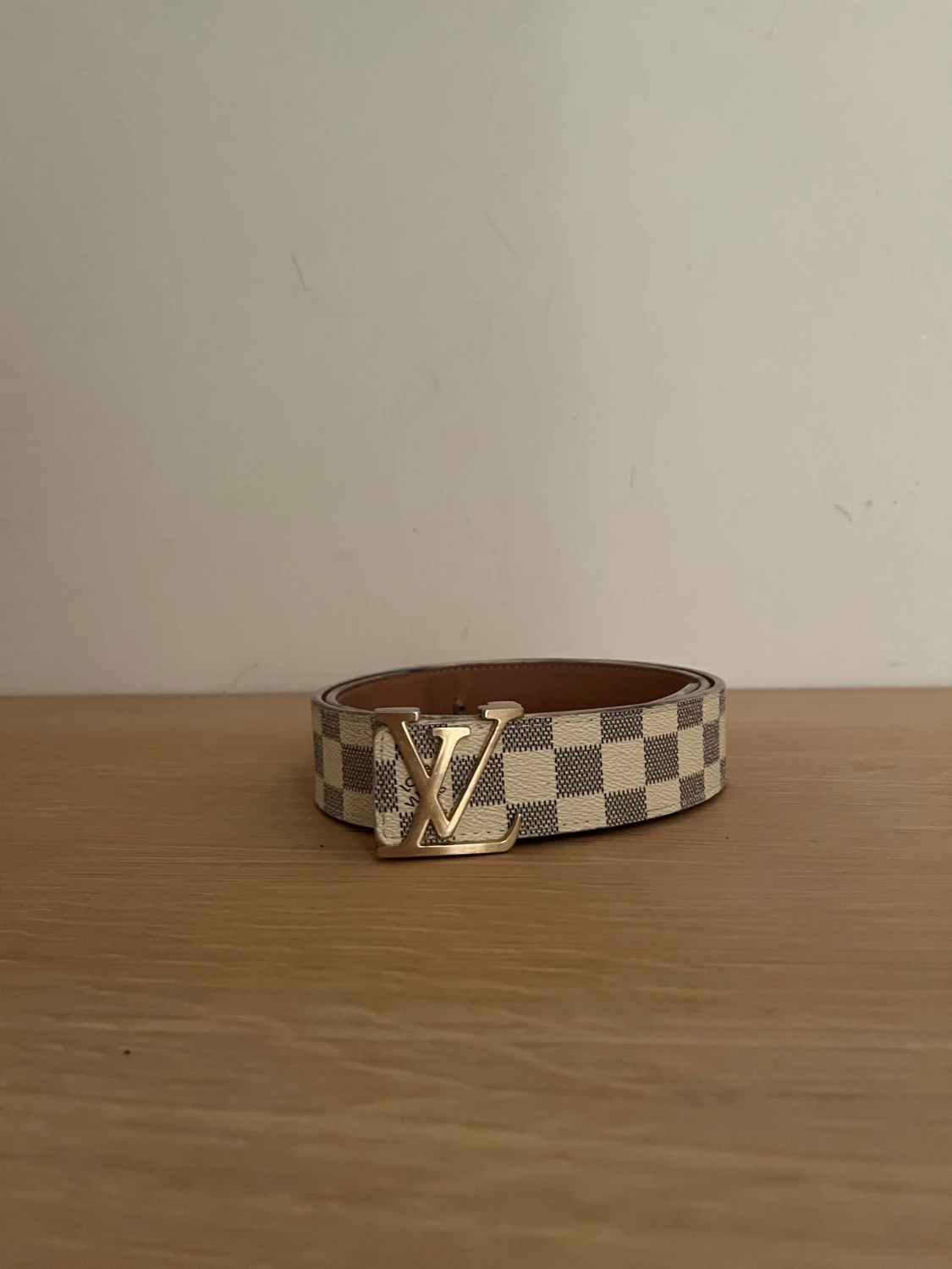 Beigest bälte med Guldigt märke.