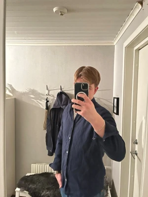 Mörkblå These Glory Days skjorta - Snygg mörkblå skjorta med klassisk krage och vita knappar. Skjortan har lång ärm och en rak passform som funkar till jeans eller chinos. Materialet ser ut att vara bomull, vilket gör den skön och lätt att bära. Perfekt för dig som gillar stilrena plagg.