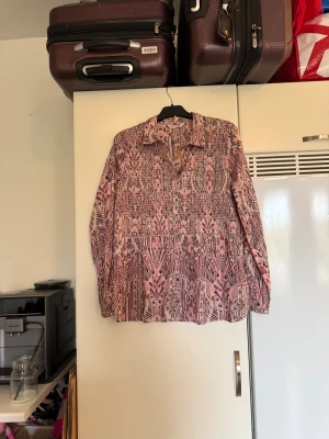 Odd molly skjorta  - Säljer en otroligt vacker skjorta i en rosa ton, den har detaljer i bland annars brun och rosa. Från märket Odd Molly. Storlek 3 som enligt deras storleksguide motsvarar en L. Helt ny med tags/ prislapp fortfarande kvar. 