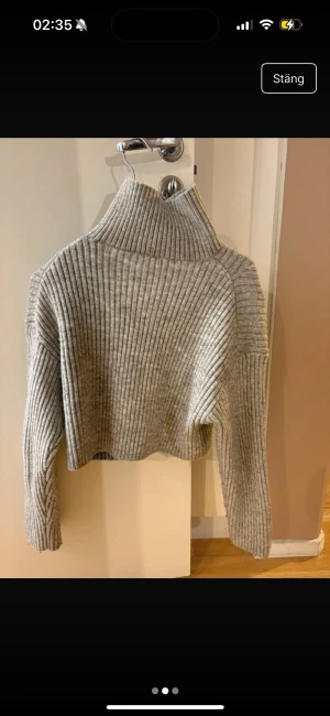 Grå ribbad polotröja från H&M - Säljer en snygg grå polotröja från H&M i storlek S. Tröjan är ribbstickad, har hög krage och är lite croppad i modellen. Perfekt för dig som gillar en chill och trendig stil. Långa ärmar och mjukt stickat material gör den superbekväm.
