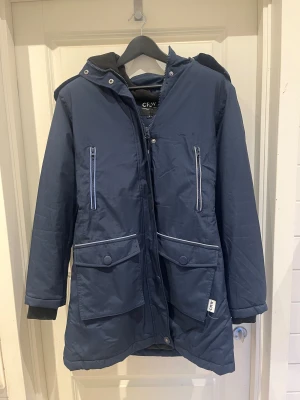 Mörkblå stalljacka till vintern från CRW - Säljer denna helt oanvända stalljacka som är perfekt varm och vädertålig nu till vintern. Lite längre än en vanlig jacka vilket gör den väldigt bekväm under kalla vinterdagar. Inköptes vintern 2023 för 799kr men har bara hängt i garderoben sedan dess, alltså inga tecken på användning. 
