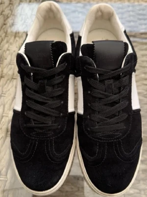 Valentino flycrew 41or - Svarta och vita Valentino sneakers med snygg kontrast mellan mocka och skinn. Klassisk rund tå, svart snörning och vit platt sula med coolt kamouflagemönster undertill. Perfekt för dig som gillar exklusiva streetwear-vibbar.