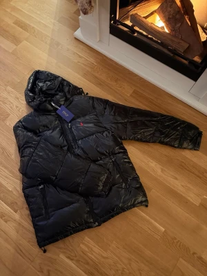 Ralph lauren jacka - Säljer nu denna helt nya glänsiga och svarta Ralph Lauren-jackan i strl S. Perfekt nu när vintern är här. Som sagt helt ny och aldrig använd. Bara att skriva ett meddelande vid intresse!