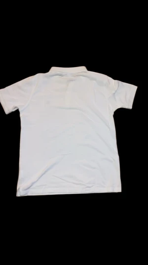 Vit pikétröja från Gant - Vit pikétröja från Gant med klassisk krage och knappar framtill. Tröjan har korta ärmar och Gant-logga broderad på bröstet. Tillverkad i 100% bomull för en skön och luftig känsla.