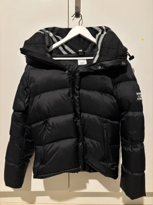 Burbery Dunjacka - Säljer en helt ny och oanvänd dunjacka från Burberry. Jackan är i perfekt skick, kommer med taggen kvar samt medföljande Burberry dust bag. Aldrig använd, endast uppackad för fotografering. Perfekt för dig som vill ha ett exklusivt och varmt ytterplagg i toppskick.