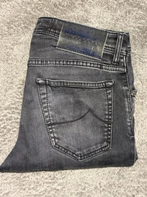 Jacob Cohen Jeans||Nick Slim - Svart/gråa Jacob Cohen||Skick 9/10||Storlek W31 lappen är avklippt men sitter som w31||Modell Nick=Slim fit||Modellen på bilden är 183 och väger 65kg||Skriv vid minsta möjliga intresse||