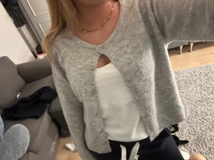 Grå kofta med knappar - Mysig grå kofta med rund hals och knappar hela vägen framtill. Koftan har en enkel och stilren design, är långärmad och tillverkad i ett mjukt stickat material som känns skönt mot huden. 