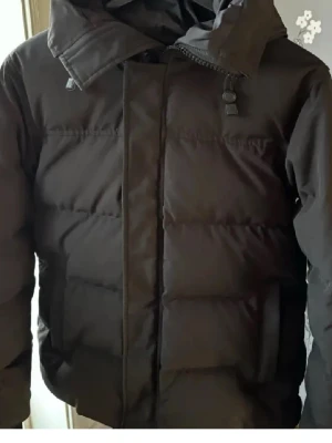 Svart pufferjack Canada Goose Macmillan  - Säljer en svart pufferjacka från Canada Goose. Jackan har använts men absolut för lite för att behålla. Den är fläckfri och i princip nyskick. Går ner i pris vid snabbköp!!!!
