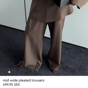 Bruna wide pleated byxor från Gina Tricot - Snygga populära ❗️SLUTSÅLDA❗️bruna kostymbyxor med breda ben och pressveck från Gina Tricot. Byxorna har midwaist och en loose passform som ger en cool och avslappnad siluett. Perfekta att matcha med en oversized kavaj för en trendig look. Helt nya med lappen kvar. 