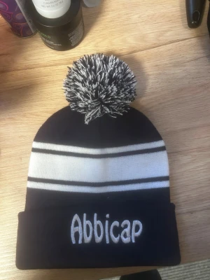 Mössa med tofs - Säljer snygga mössor med stor fluffig tofs på toppen. Finns i svart och marinblå med vita ränder. Mössorna har en klassisk form och är stickade i mjukt material, perfekta för kalla dagar. Passar dig som vill hålla sig varm i vinter.