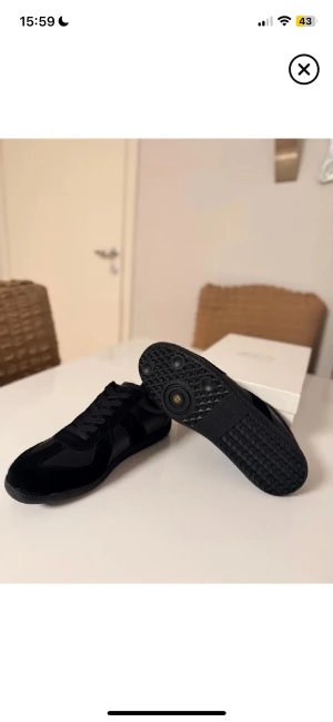 Svarta Maison skor -  helsvart med snygga paneler i mocka och skinn. Klassisk siluett med rund tà, platt sula och snörning. Diskret branding pà plösen och insidan. Perfekta for dig som gillar minimalistisk och stilren design.