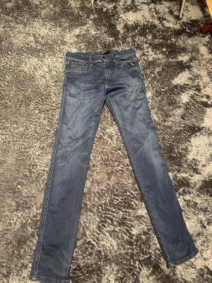 Replay Anbass jeans blå 31/34 - Snygga blå Replay Anbass jeans med klassisk femficksdesign och raka ben. Jeansen har normal passform och är tillverkade i mjukt denim-material. Perfekt för dig som gillar stilrena och tidlösa jeans med diskreta detaljer.