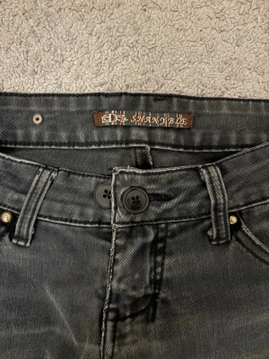 Svarta/gråa lågmidjade jeans - Säljer ett par gråa/svarta jeans med väldigt coola detaljer. Väldigt låg midja! Byxorna är något tajtare men inte skinny! Säljer då dem är för små för mig! Skulle rekommendera till en xxs-xs💘