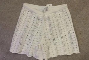 Vita stickade shorts från Amisu - Superfina vita stickade shorts från Amisu med snyggt hålmönster och snörning i midjan. Perfekta för varma dagar. Shortsen har en lätt vågig kant nertill och känns både trendiga och bekväma.