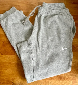 Nike mjukisbyxor strlk L - Grå Nike mjukisbyxor i storlek L. Fickor i sidorna, backficka med tryckknapp o dragsko i midjan. Felfritt skick. Djur- o rökfritt hem. 