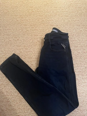 Mörkblå Replay jeans, storlek 32/32 - Snygga mörkblå jeans från Replay i klassisk straight fit. Modellen har fem fickor, bälteshällor och subtil Replay-logga vid fickan. Jeansen är tillverkade i slitstarkt denim och passar dig som gillar en tidlös look med lite edge.