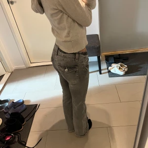 Lågmidjade jeans - Säljer dessa ljusgråa lågmidjade bootcut jeans från ginatricot. Köpta på 14+ avdelningen i storlek 152. Passar mig perfekt som vanligtvis har storlek 32, xs. Fina knappar på fickorna baktill.  Skick 10/10, sparsamt använda.  Nypris: 399kr 