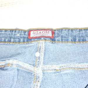 Blå cargopants från Miaoni High Fashion - Snygga ljusblå cargopants från Miaoni High Fashion med coola fickdetaljer och bältesrem på ena benet. Klassisk jeanslook med kontrastsömmar och flera fickor som ger en streetkänsla. Perfekt för dig som gillar avslappnad stil.