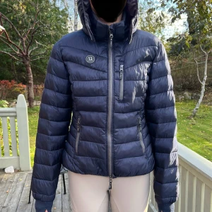 Höst/vinter- jacka från Uhip - Jättesnygg och varm jacka från uhip. Storlek 40, säljes då den är för stor för mig. Den ser inte så stor ut på bilden men är storleksttrogen och passar M-L. Har du mindre storlek är den perfekt för att få plats med tjockare fleece under.  Nypris 1600 kr.  Sparsamt använd och i mycket bra skick. Perfekt för kalla stalldagar. Luvan går att ta av, och den har reflexer. 