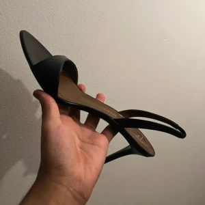 Svarta sandaler från Giuseppe Zanotti - Stilrena svarta sandaler från Giuseppe Zanotti i äkta skinn. Modellen har öppen tå, smal rem över foten och en elegant låg klack. Perfekt för dig som gillar minimalistisk och lyxig design. Snygg italiensk kvalitet och klassisk look. Köpta från NK