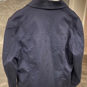 Mörkblå overshirt med dragkedja - Snygg mörkblå overshirt från Newhouse med klassisk krage, två bröstfickor med knappar och dragkedja framtill. Jackan är tillverkad i bomull och har långärmad design. Perfekt för dig som gillar stilrena och enkla plagg.