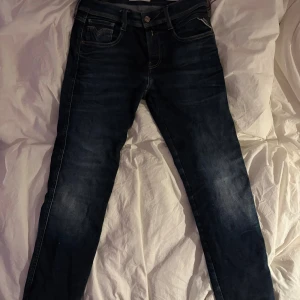 Replay Anbass Hyperflex jeans blå 30/32 - Snygga Replay Anbass Hyperflex jeans i mörkblå tvätt med klassiska fem fickor och coola kontrastsömmar på bakfickorna. Slim fit-modell med stretchigt material som ger grym komfort. Perfekta för dig som gillar stilrena och moderna jeans.