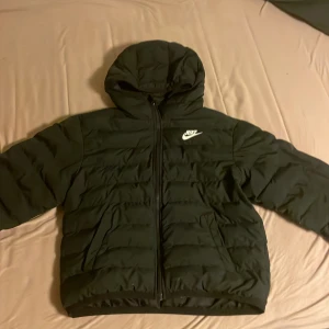 Svart pufferjacka från Nike med huva - Säljer en svart pufferjacka från Nike med huva och dragkedja framtill. Jackan har ett vitt Nike-logga på bröstet. Jag har växt ur den så nått o ge till små syskonen. Kan gå ner i pris vid snabb affär 