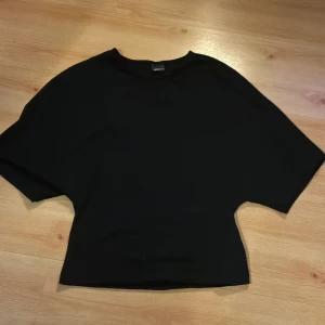 Svart topp från Gina Tricot, S - En stilren svart topp från Gina Tricot i storlek S. Toppen har en formad passform med korta ärmar och rund halsringning. Perfekt att matcha med jeans eller kjol för en enkel och snygg look. Säljer för jag inte tycker om hur den sitter på mig 🥰använd 1 gång och den är i nyskick💓pris kan även diskuteras 