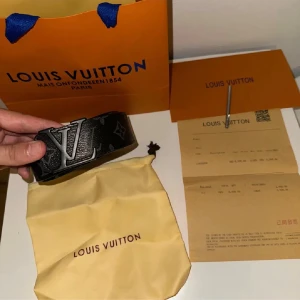 Svart Louis Vuitton bälte  - Säljer ett svart Louis Vuitton bälte med klassiskt monogrammönster och stor LV-logga i metall framtill. Bältet är gjort i skinn och har en exklusiv känsla, perfekt för att lyfta vilken outfit som helst. Kommer med originalpåse och kvitto.