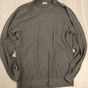 FILIPPA K Grå stickad Tröja med stripes [M]  - Säljer en stilren grå stickad tröja från Filippa K. Tröjan har rund halsringning, lång ärm och en diskret struktur i materialet. Perfekt för lager-på-lager och enkel att matcha med jeans eller chinos.