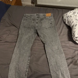 Grå jeans från Woodbird, storlek 34W/34L - Säljer ett par snygga grå jeans från Woodbird i modellen Ourganic Capsule. Jeansen har klassisk femficksdesign, raka ben och en cool tvättad look. Tillverkade i denim med hållbarhetsfokus. Perfekta för dig som gillar stilrena och moderna jeans. Har använts några fåtal gånger. Priset är diskuterbart!