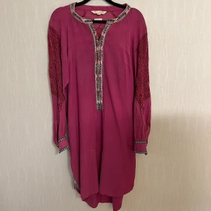 Rosa boho-klänning/ tunika med broderi från Odd Molly Sample - Säljer en cerise långärmad klänning/tunika från Odd Molly med snygga broderade detaljer i svart och rött på ärmar och rygg. Klänningen har v-ringning med knyt och mönstrade kanter. B armhåla till armhåla 47 cm, L 97 cm. Sample!