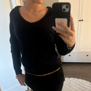 Svart v-ringad stickad tröja - En svart stickad tröja med v-ringning och långa ärmar. Enkel och stilren modell som är lätt att matcha till olika outfits. Perfekt för dig som gillar en klassisk och clean look.