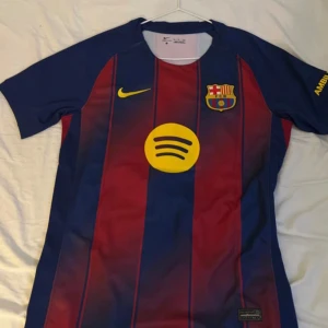 FC Barcelona Lamine Yamal Nike tröja - Säljer en FC Barcelona matchtröja med Lamine Yamal och nummer 10 på ryggen. Tröjan är kortärmad, har klassiska blå och röda vertikala ränder, gult Nike-märke och klubbemblem på bröstet. Materialet är lätt polyester, perfekt för fotboll eller häng med polarna. Hör gärna av vid frågor!! Mvh