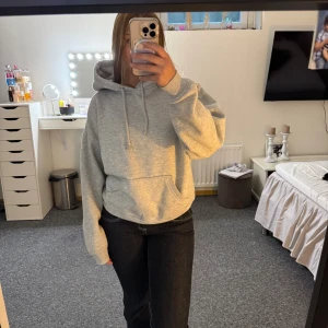 Grå oversized hoodie med huva - Säljer en grå oversized hoodie med huva och snörning. Tröjan har en stor magficka och långa ärmar med avslappnad passform. Perfekt för chill dagar och enkel att matcha med jeans eller mjukisbyxor.
