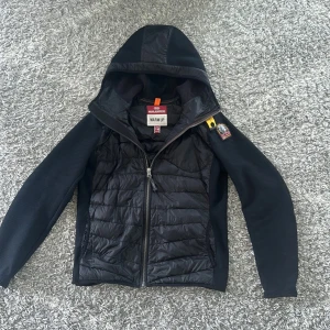 Parajumper cardigan  - Svart cardigan från Parajumpers med huva, quiltad front och släta ärmar. Cardiganen är extremt bekväm att bära i lite kyligare väder som till exempel på hösten och våren. Knappt använd, Y-M. Ny pris 4500kr, mitt 2500kr. Priset ej hugget i sten så kom med ett prisförslag.