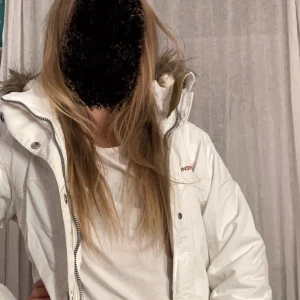 Vit vinterjacka från Didriksons ✌️✌️✌️ - Snygg vit vinterjacka från Didriksons med mysigt teddyfoder och huva med fuskpäls. Jackan har dragkedja, knappar och stora fickor framtill. Perfekt för kalla dagar och har en stilren look som funkar till allt!